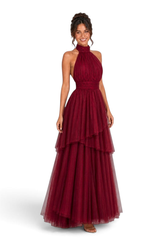 Pink shop by maf wine red tulle halter gown with a bow neck and asymmetrical tiered skirt on a smiling model
