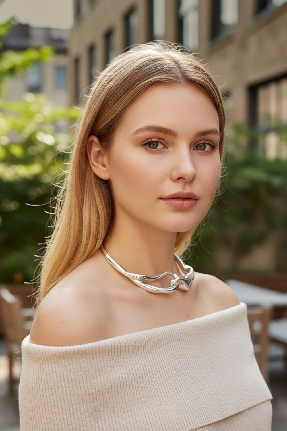 Choker rígido plateado con nudo orgánico de Pink shop by maf, lucido por una modelo con top beige en exterior.