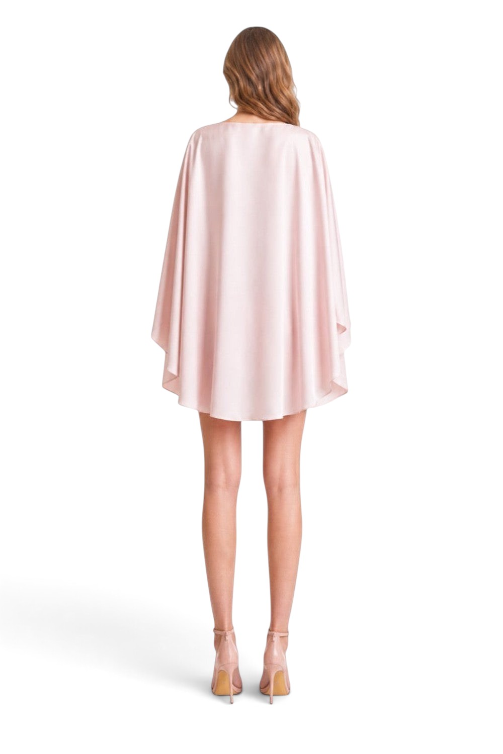 Back view of a model wearing a Pink shop by maf baby pink satin cape top and 3D floral mini skirt with heels.