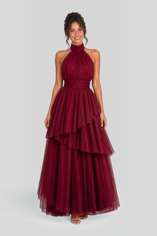 Pink shop by maf wine red tulle halter gown with a bow neck and asymmetrical tiered skirt on a smiling model
